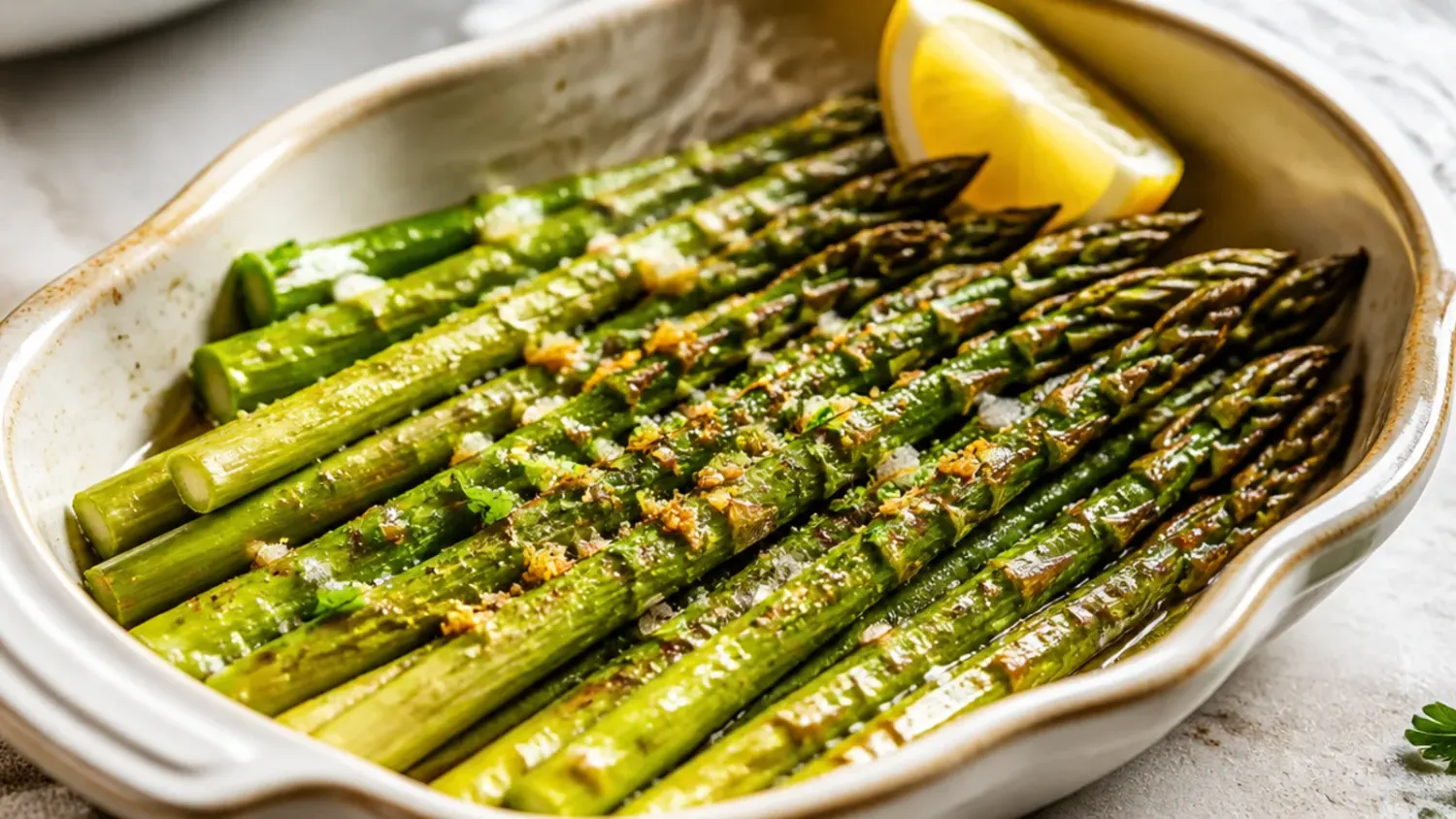 Golden roasted asparagus spears topped with melted parmesan and breadcrumbs on a baking sheet, fresh from the oven