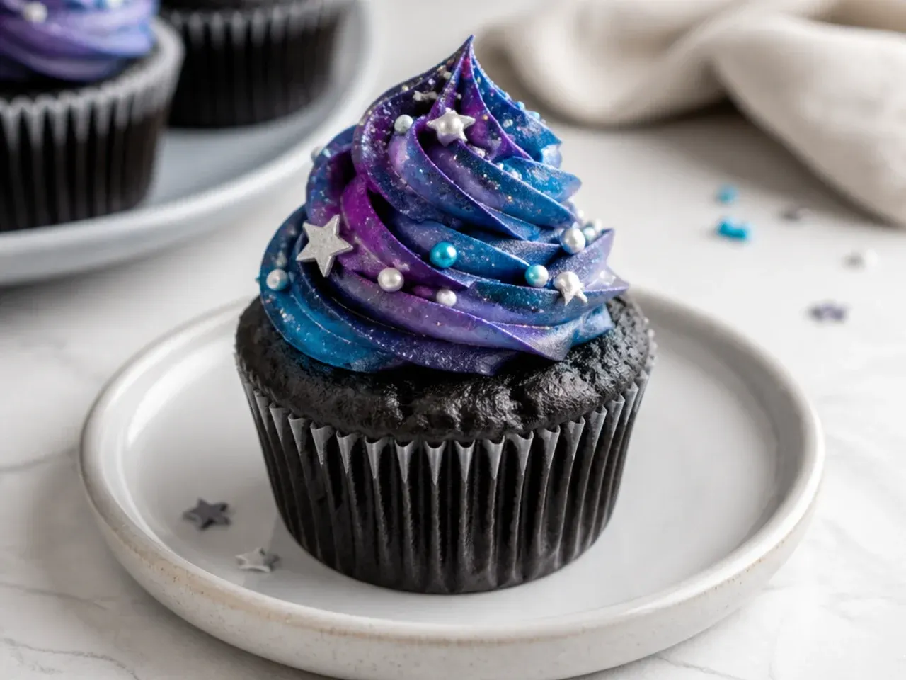 Whimsical galaxy black cupcakes with swirled purple and blue nebula frosting