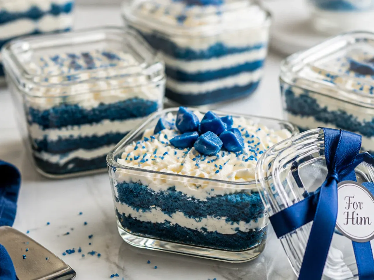 A blue layer cake stored in a clear airtight container on a kitchen counter