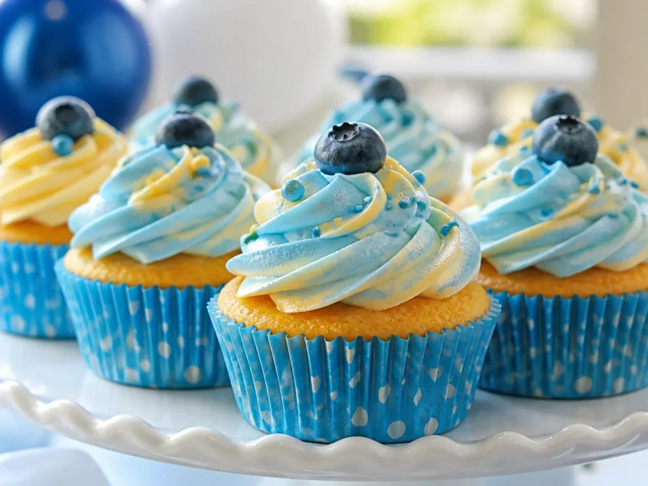 Children decorating their own cupcakes with bowls of blue, white and orange buttercream and sprinkles on a table