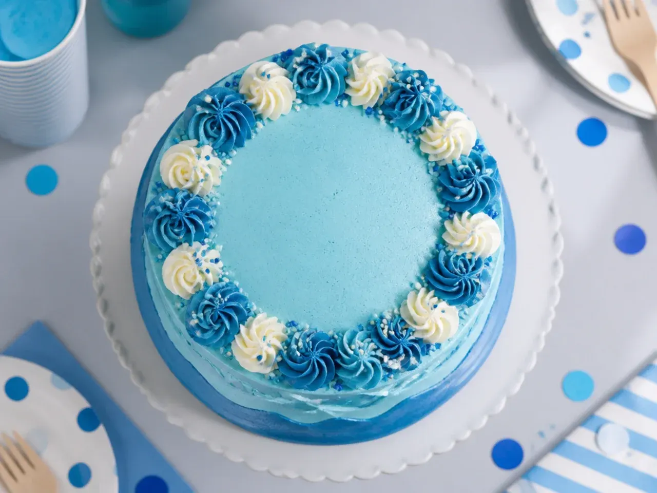 Round cake with pale blue buttercream on top and a darker navy blue band around the bottom edge