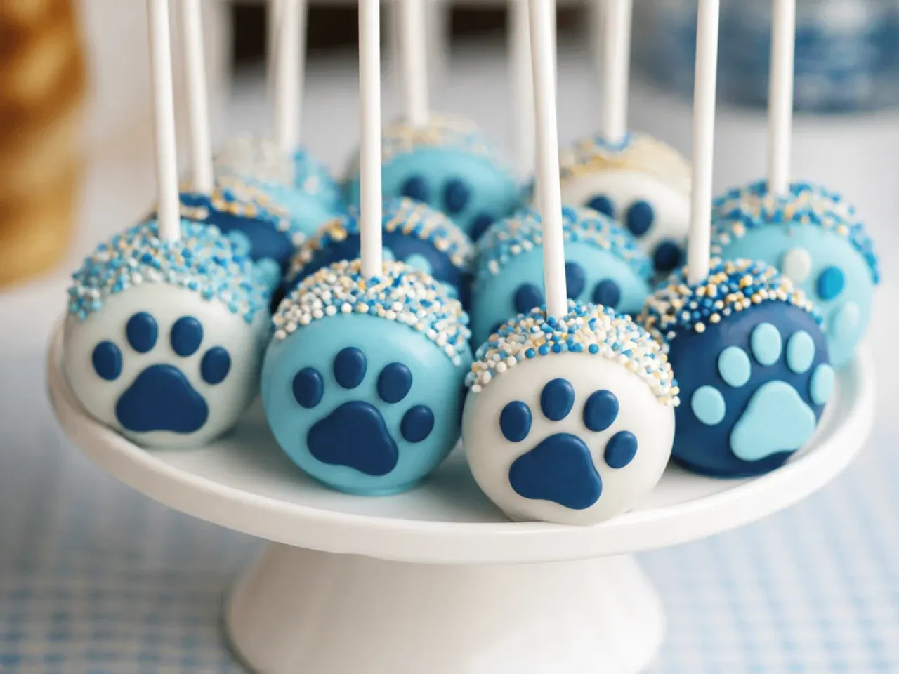 Cake pop topped with a white fondant paw print design against a blue candy shell