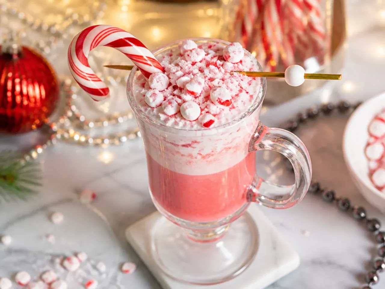 Candy cane cocktail in a martini glass with a crushed candy cane rim and mini candy cane garnish