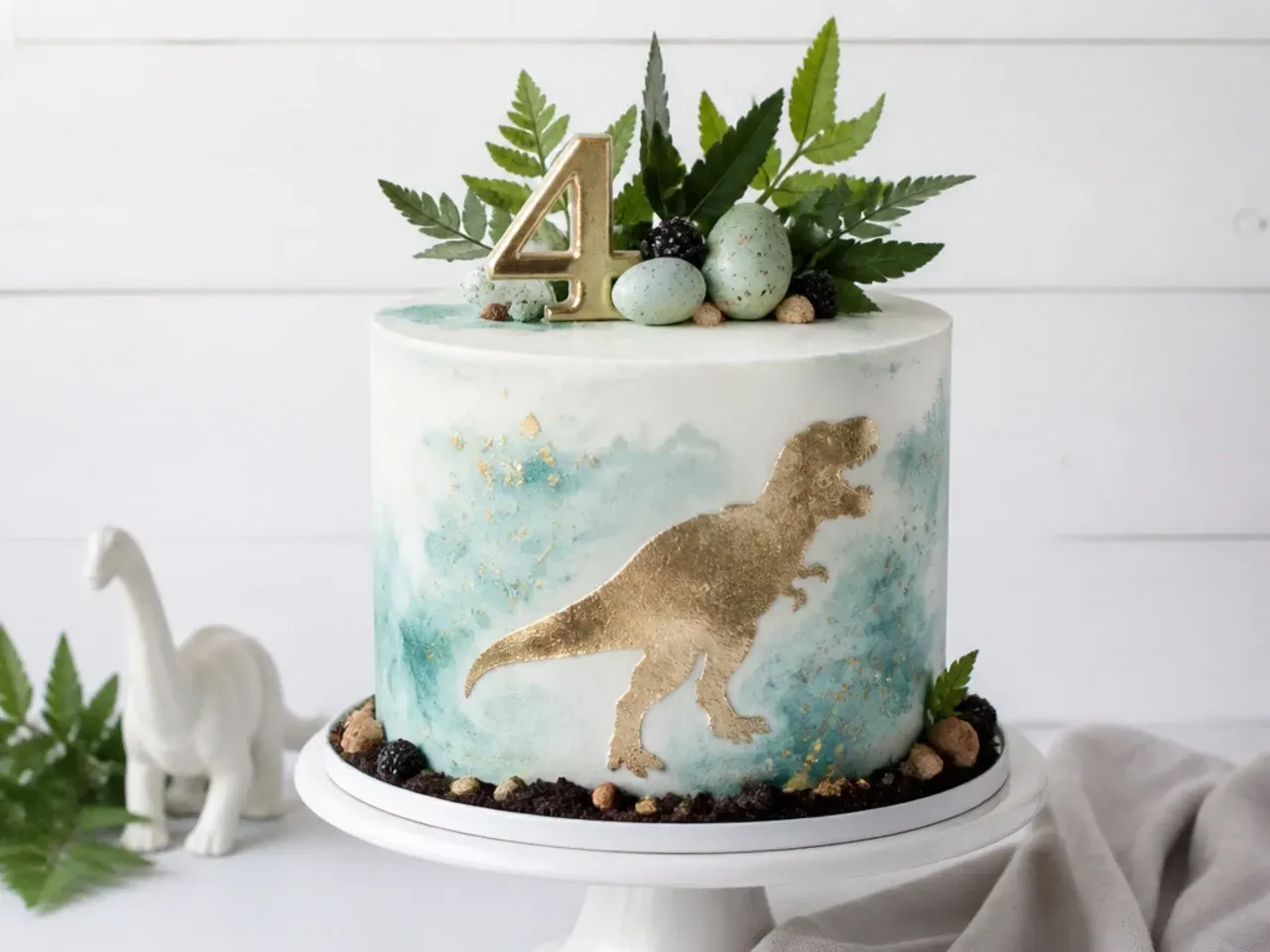 Elegant watercolor fondant dinosaur cake with gold painted silhouette