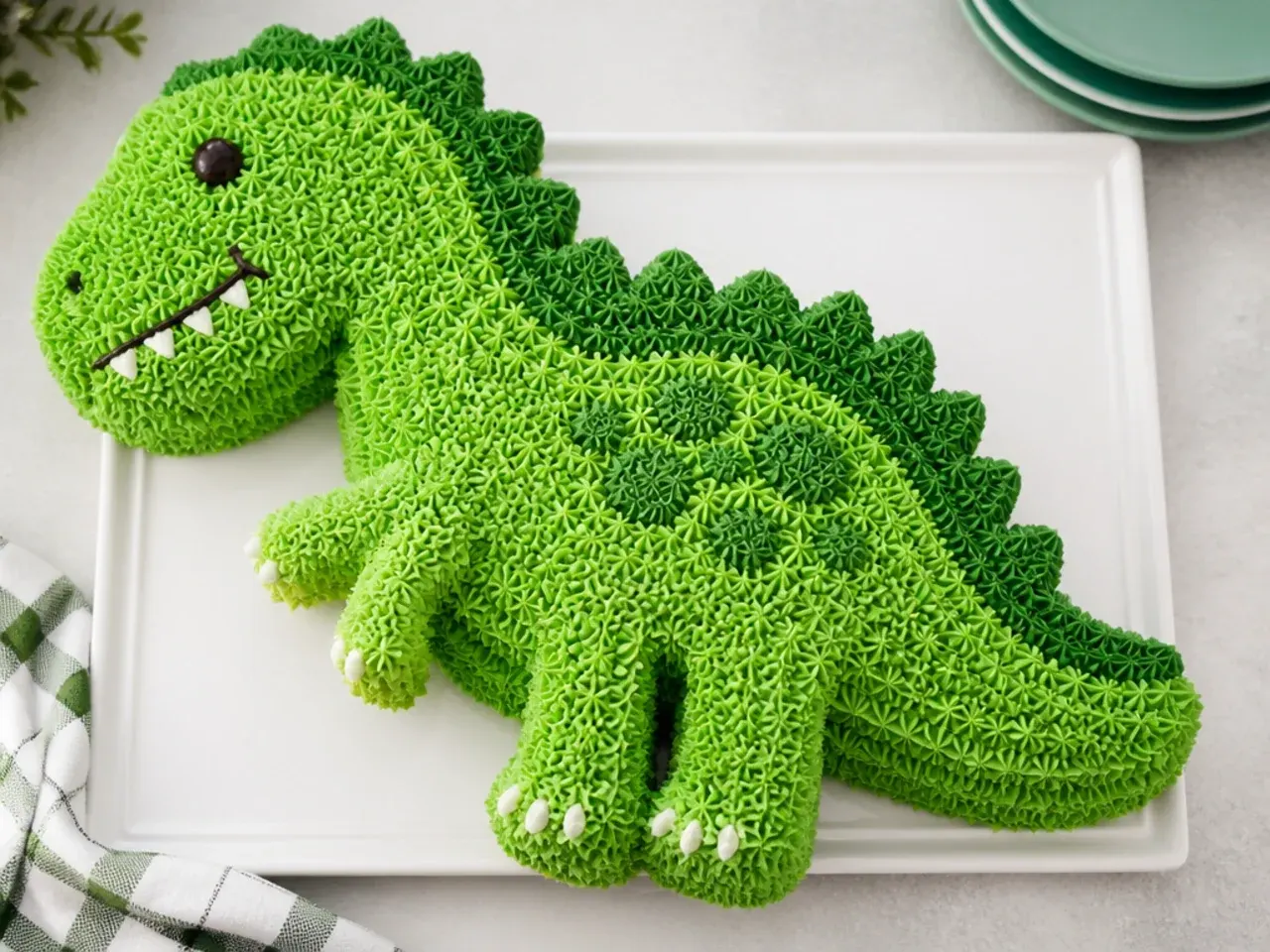 Classic star-piped dinosaur shaped pan birthday cake in two shades of green