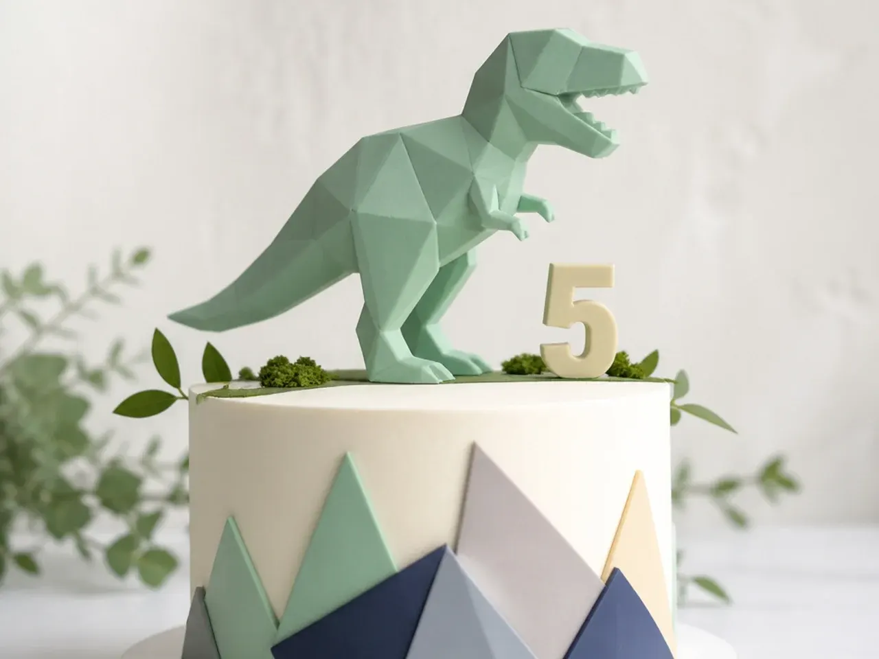 Modern geometric low-poly dinosaur cake topper in matte pastel fondant