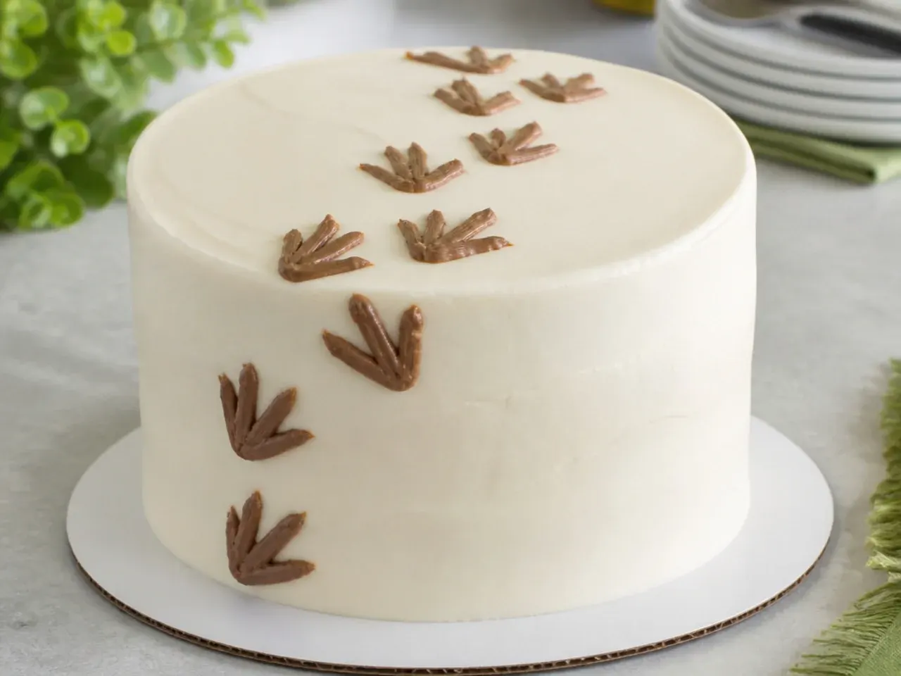 Charming dinosaur footprint trail cake topper piped in brown icing