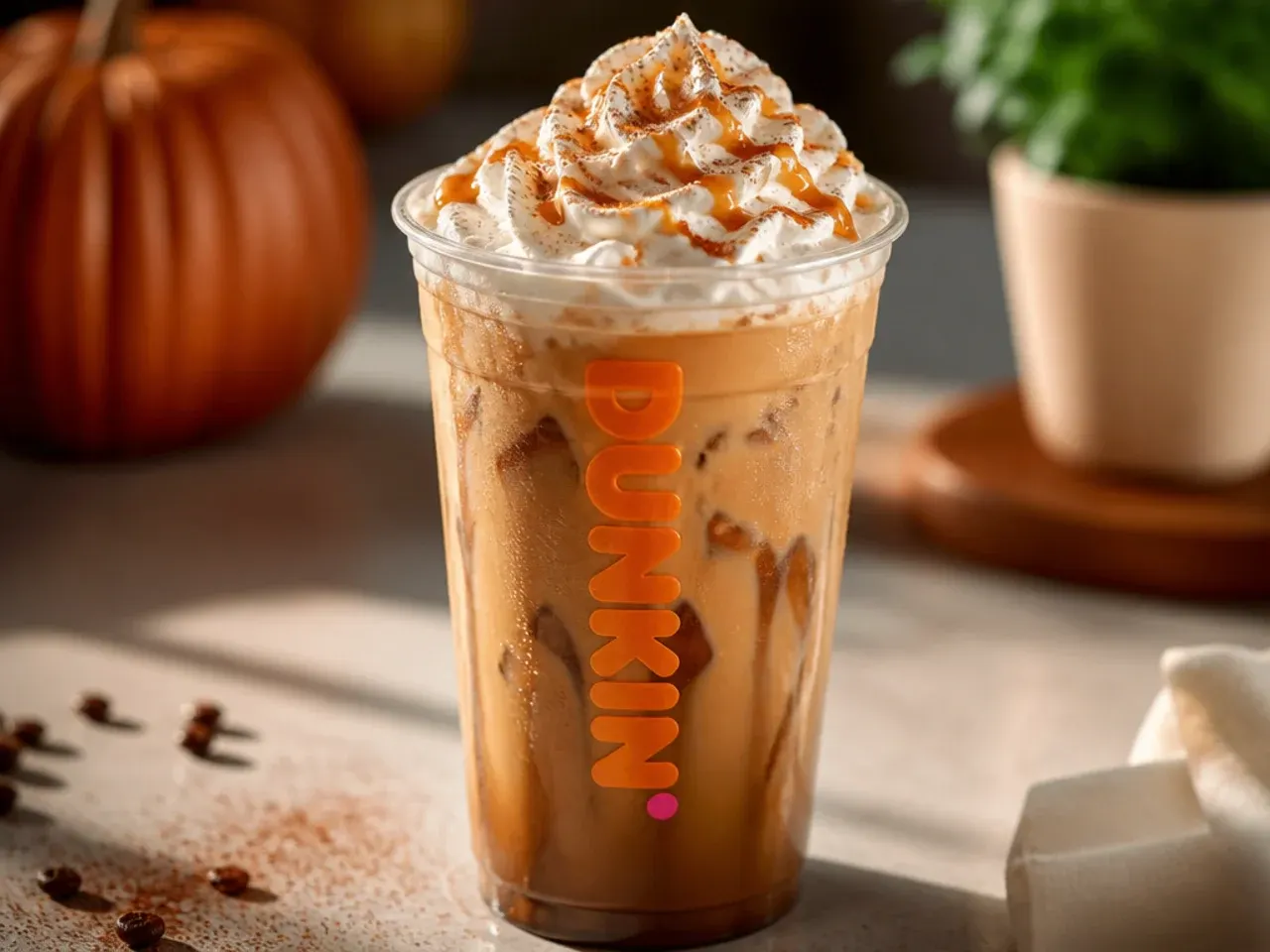 Overhead shot of several cozy copycat Dunkin fall drinks arranged on a wooden table with cinnamon sticks and coffee beans scattered around