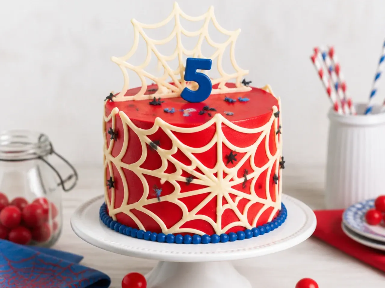 Delicate Spiderman cake decorated with white chocolate web panels on red frosting