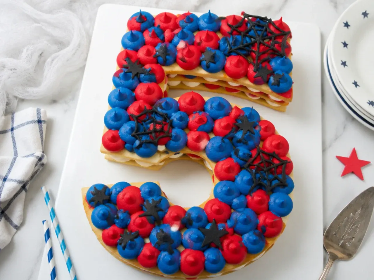 Charming Spiderman number cake with red and blue buttercream dollops and web accent