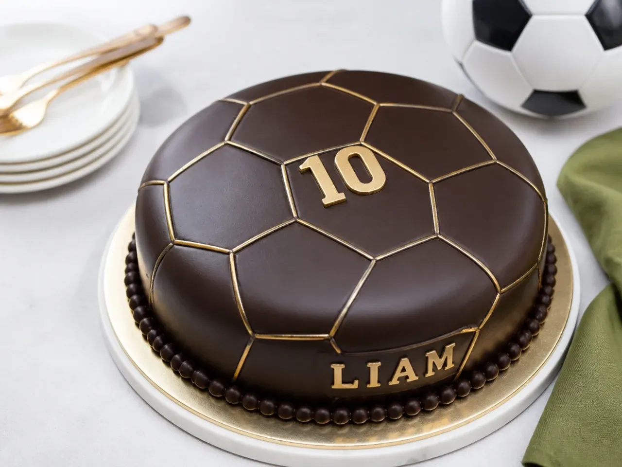 Elegant chocolate ganache football cake for boys with gold seam accents