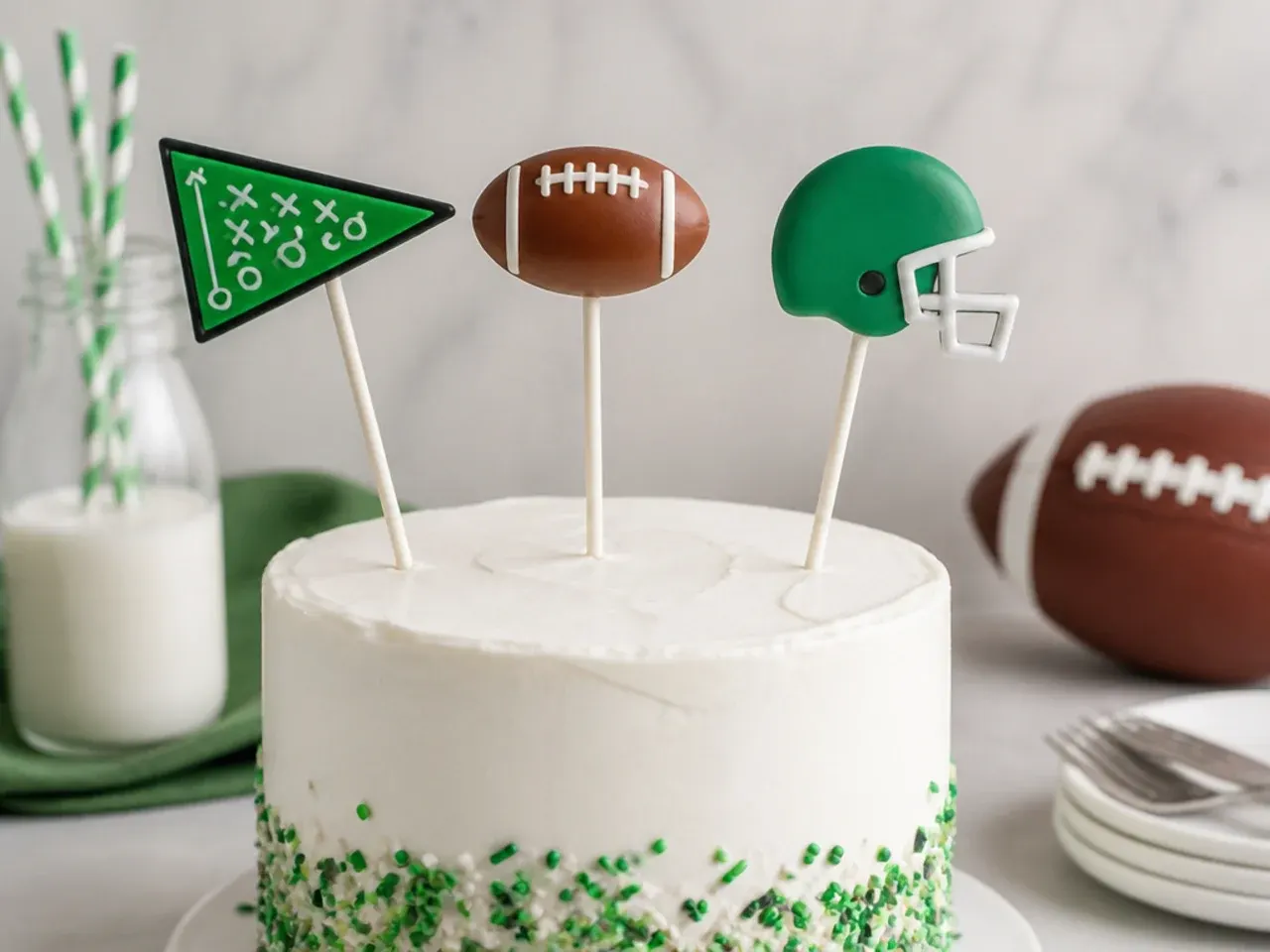 Playful football cake pop toppers on sticks above a birthday cake