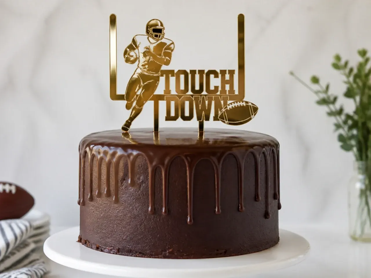 Elegant metallic gold football cake topper on a dark chocolate cake
