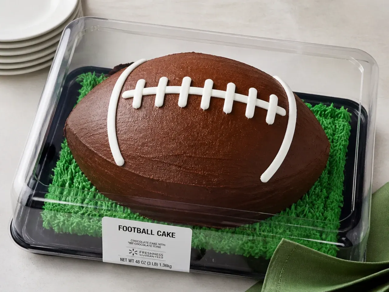 Store-bought football cake from a grocery bakery with pre-piped laces in a plastic box
