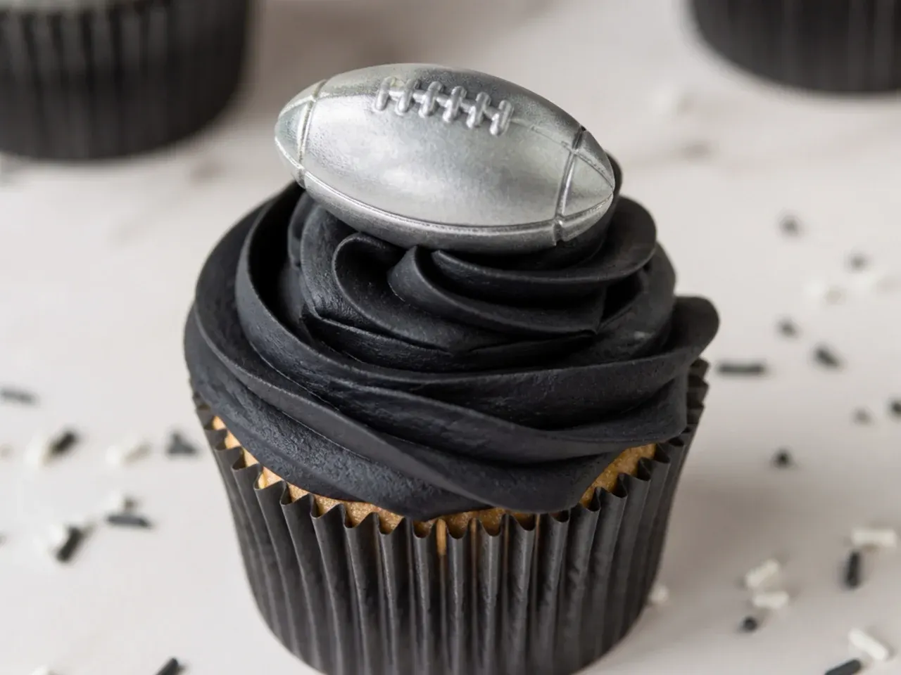 Bold blackout football cupcakes with matte black buttercream and a metallic silver football