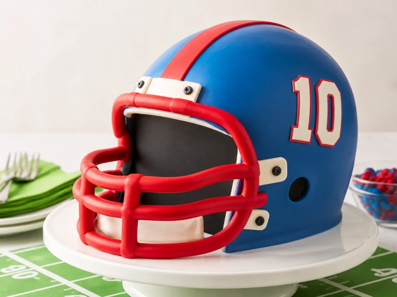 Playful cartoon football helmet cake with an oversized fondant facemask in bright primary colors