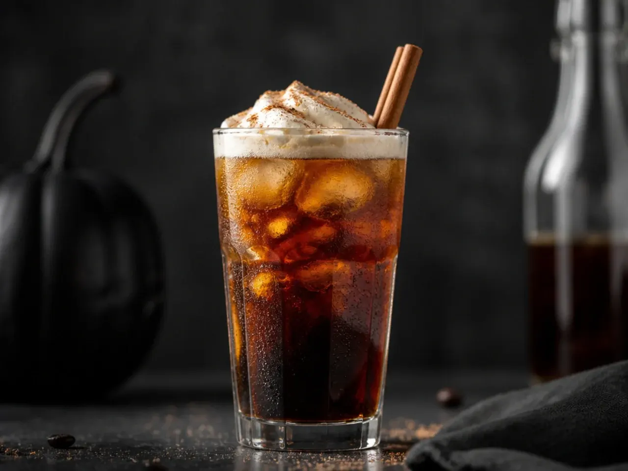Jet black cold brew coffee with swirling white oat milk marbling in a clear glass over ice