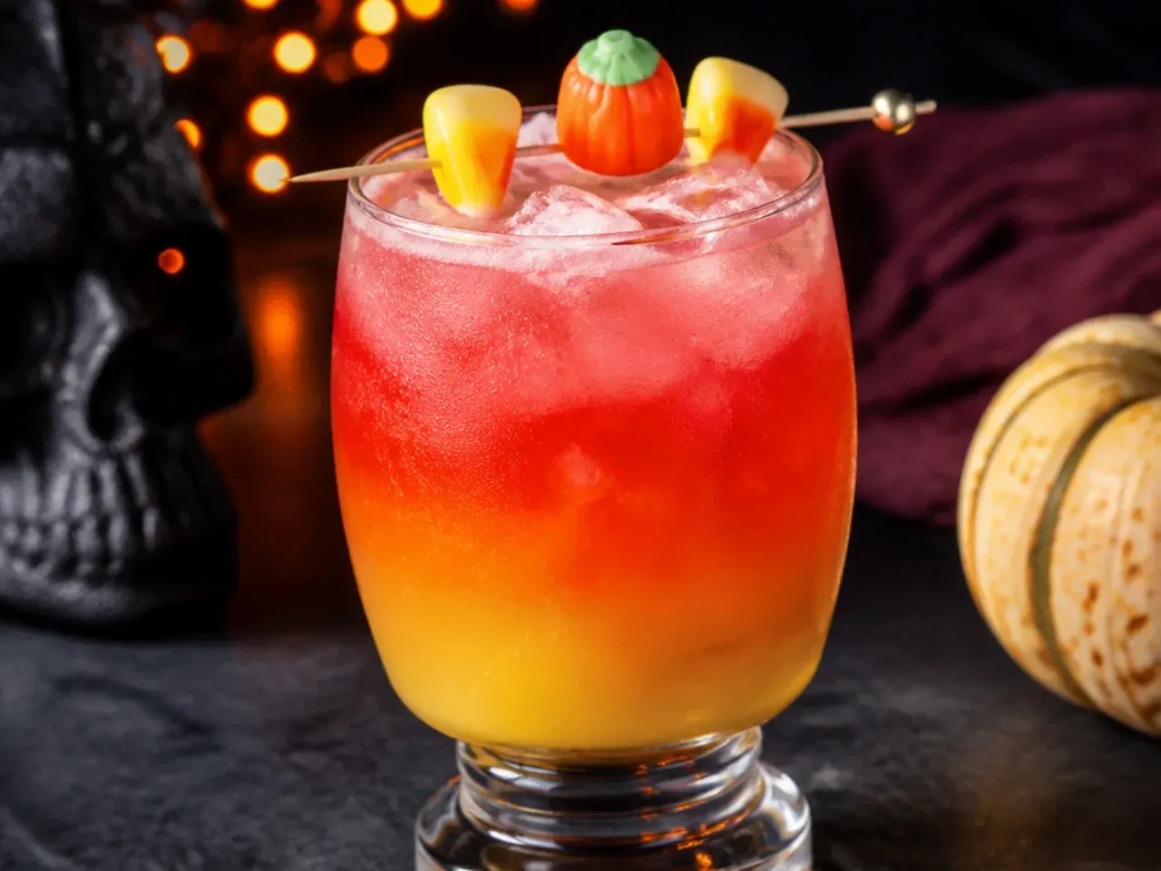 Layered orange, yellow, and white candy corn striped drink in a clear glass