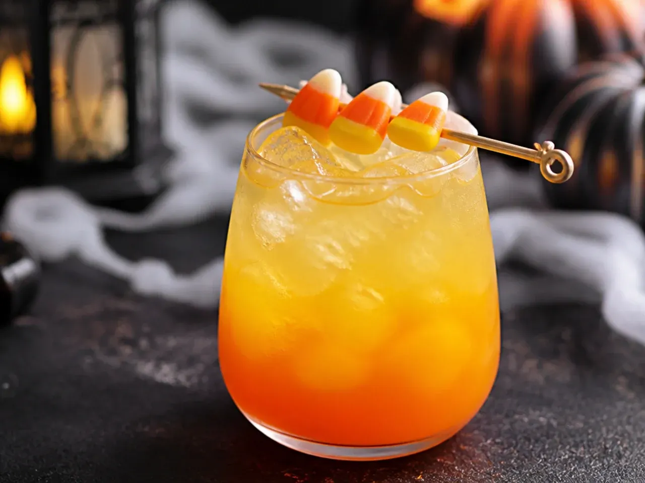 Tall glass showing three distinct orange, yellow and white layers of a candy corn drink