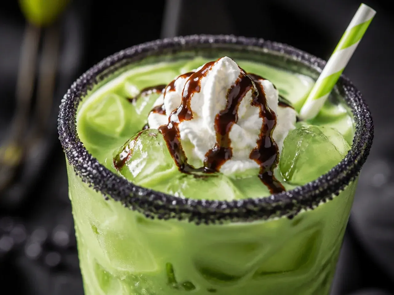 A green Frankenstein frappuccino topped with whipped cream and chocolate stitch marks