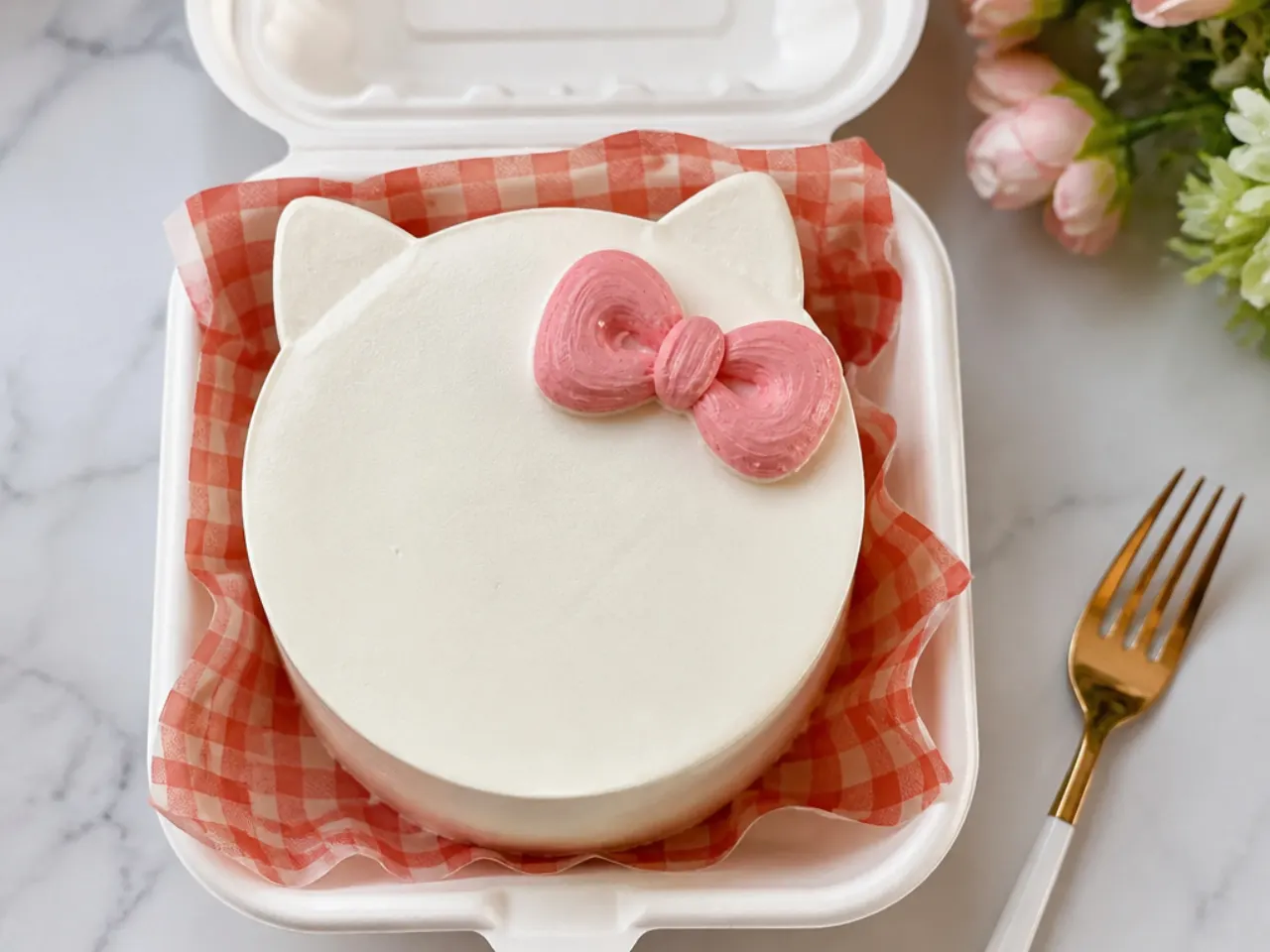 Minimal Hello Kitty bento cake with a single piped bow and ear silhouette