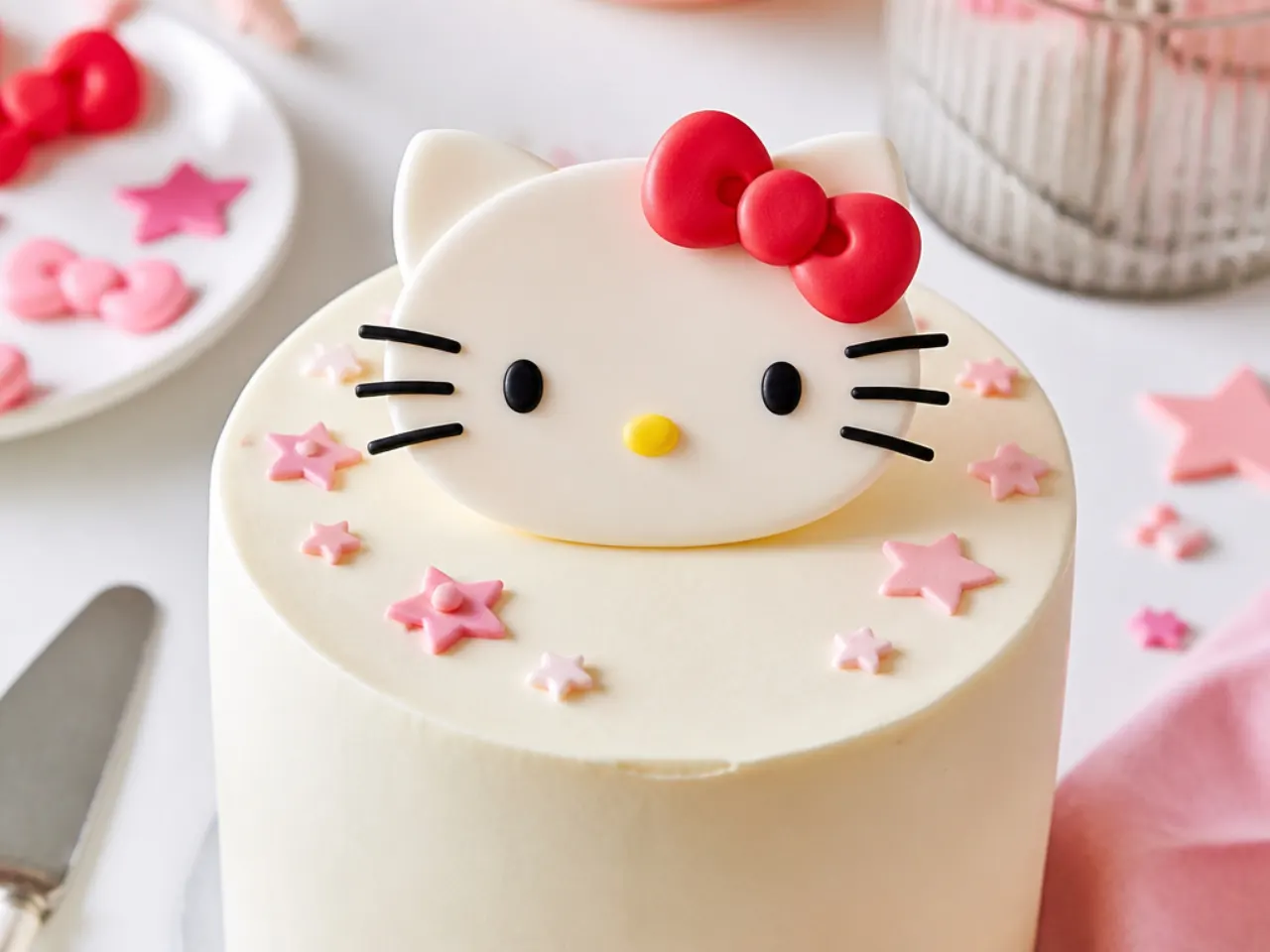 Easy beginner Hello Kitty cake topper shaped from simple fondant circles and a red bow