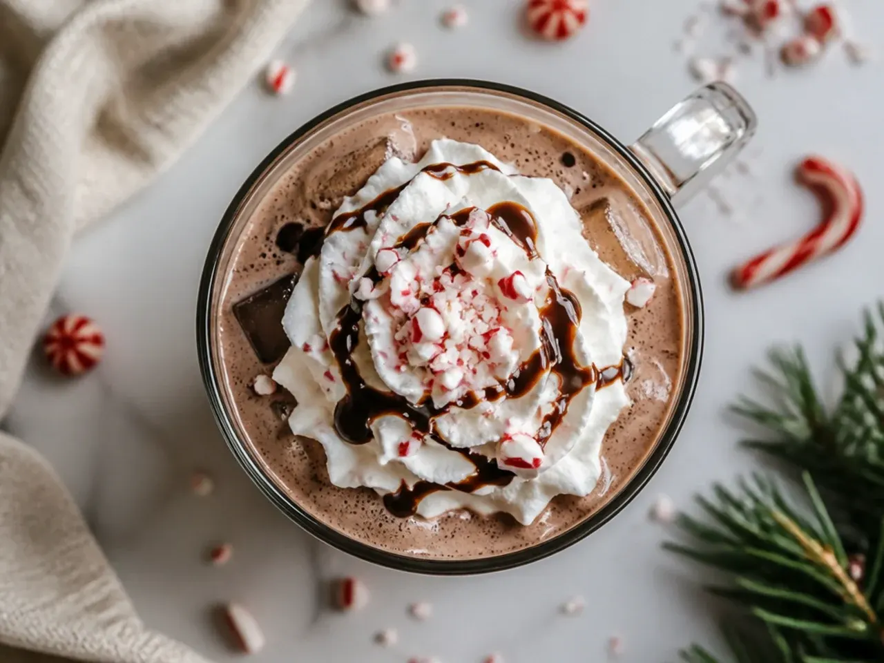Glass of iced peppermint cocoa cooler topped with whipped cream and a candy cane stirrer
