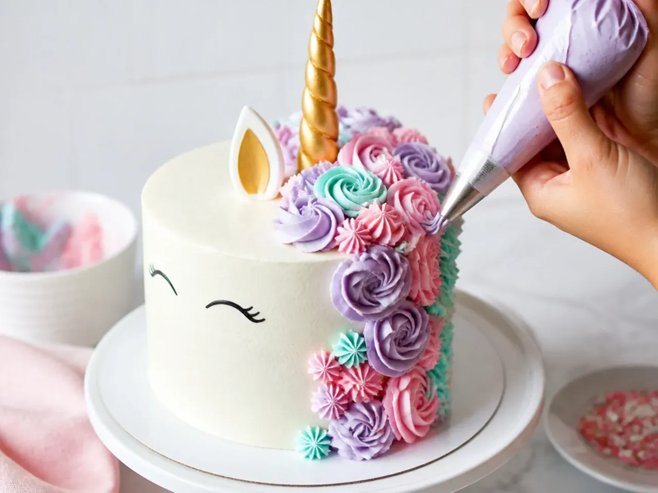 Piping a cascading pastel buttercream mane on a homemade unicorn cake