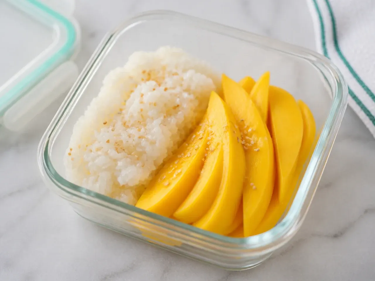 Meal-prep containers of make-ahead rice cooker mango sticky rice with sliced mango