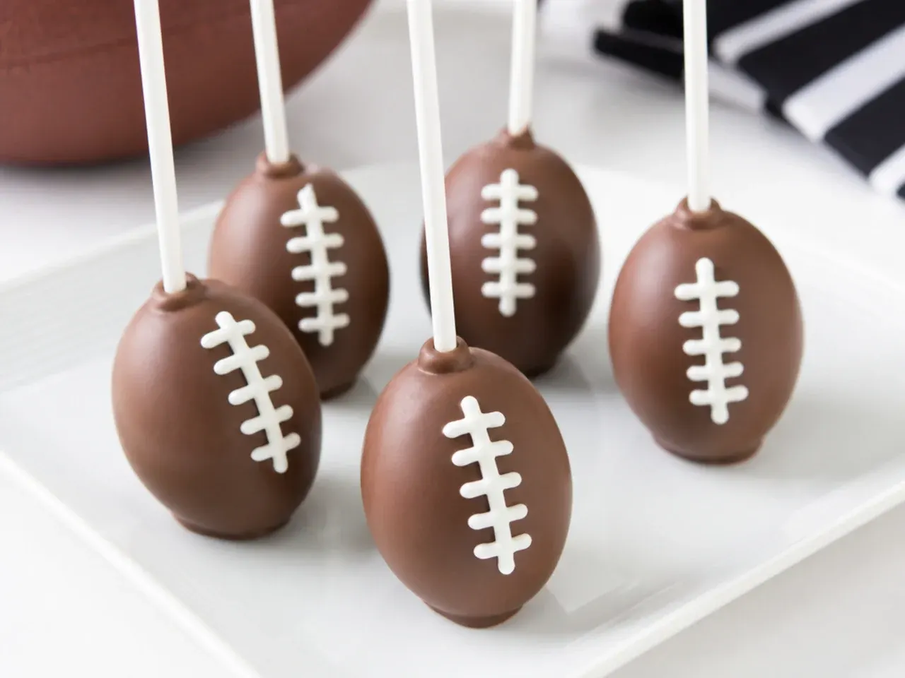 Whimsical football-shaped cake pops dipped in chocolate with white candy laces