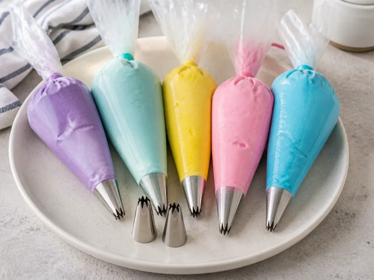 Tinted buttercream bags and piping tips prepared for a mini unicorn cake