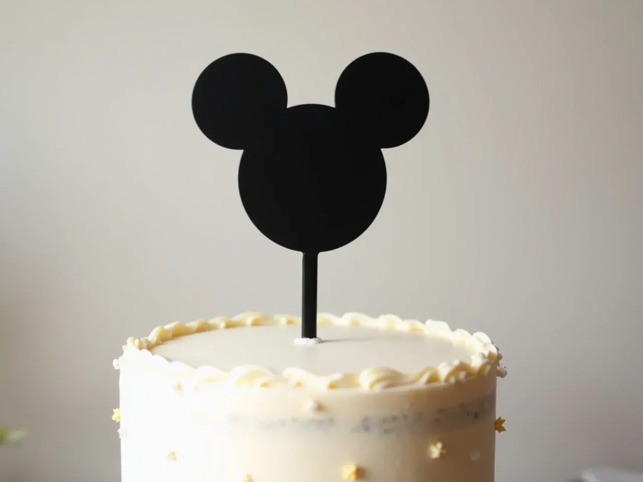 Modern minimalist black Minnie Mouse silhouette cake topper on white buttercream