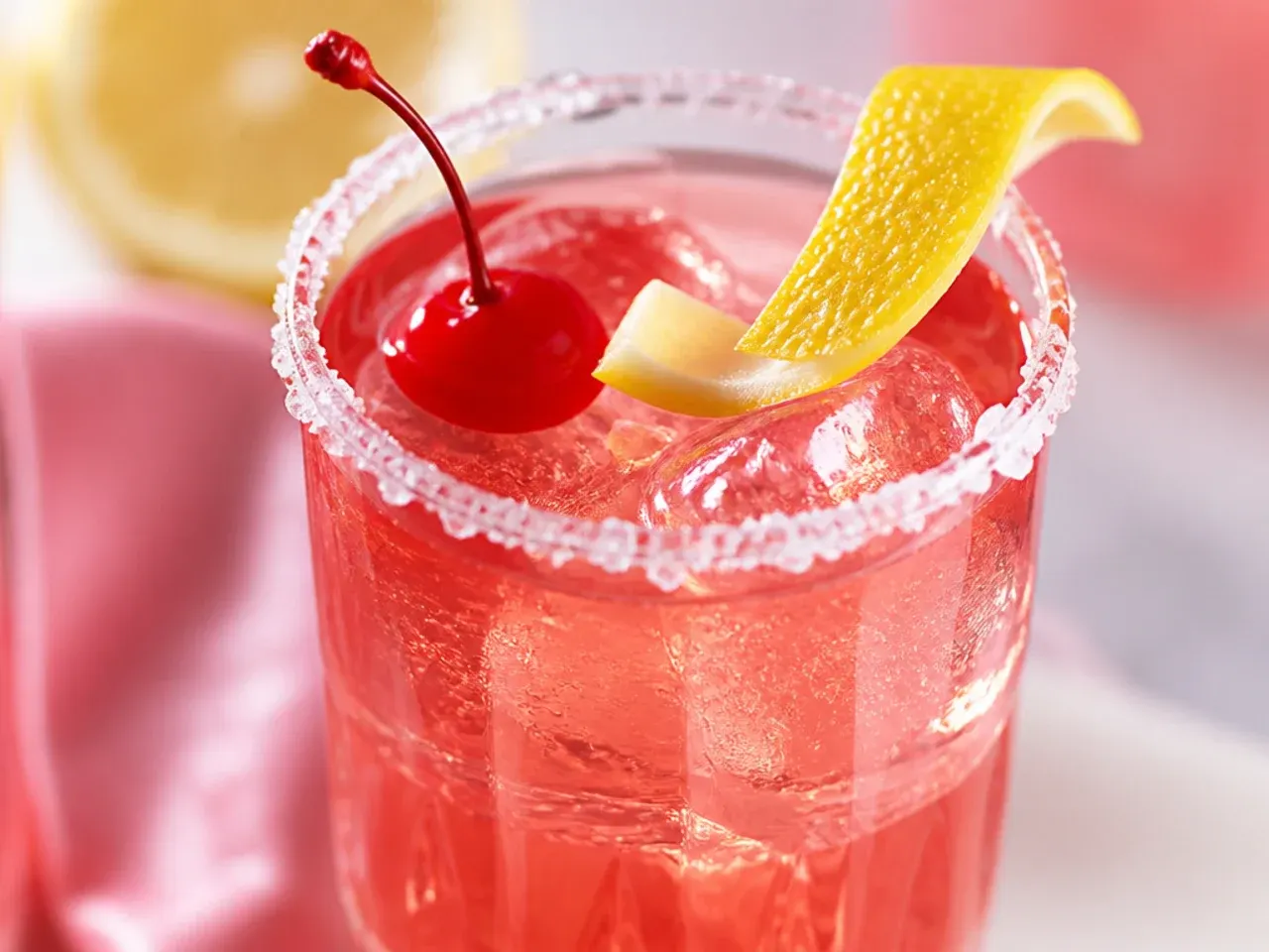 Shirley Temple mocktail with a red-to-gold gradient, cherry, and orange wheel garnish