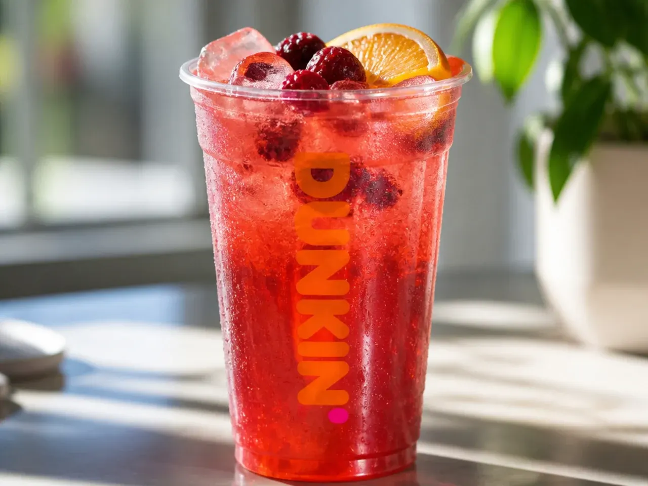 Overhead shot of ingredients for non coffee Dunkin drinks laid out on a kitchen counter, including green tea, fruit purees, milk and ice