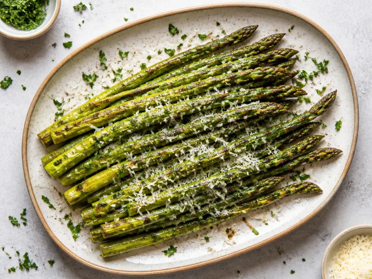 Thick roasted asparagus spears seasoned with dried herbs on a rustic tray
