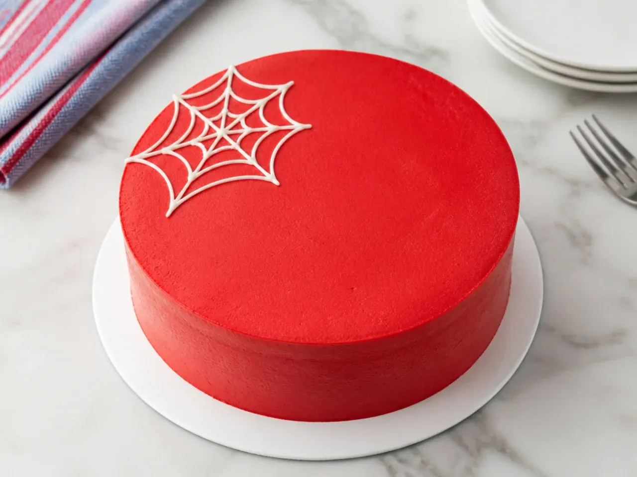 Minimal red Spiderman cake with a single small buttercream web in one corner