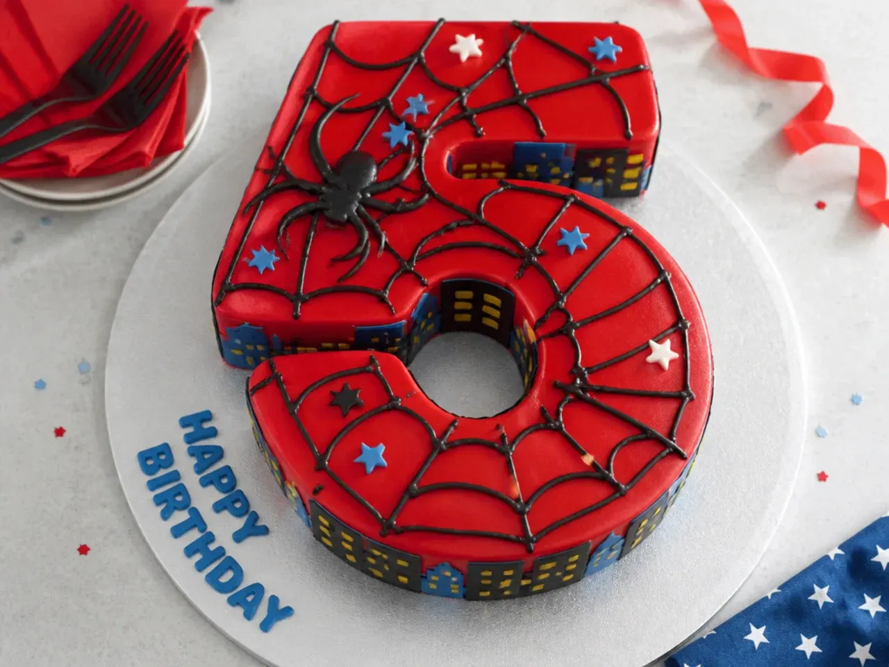Whimsical number-shaped Spiderman birthday cake with red icing and web pattern
