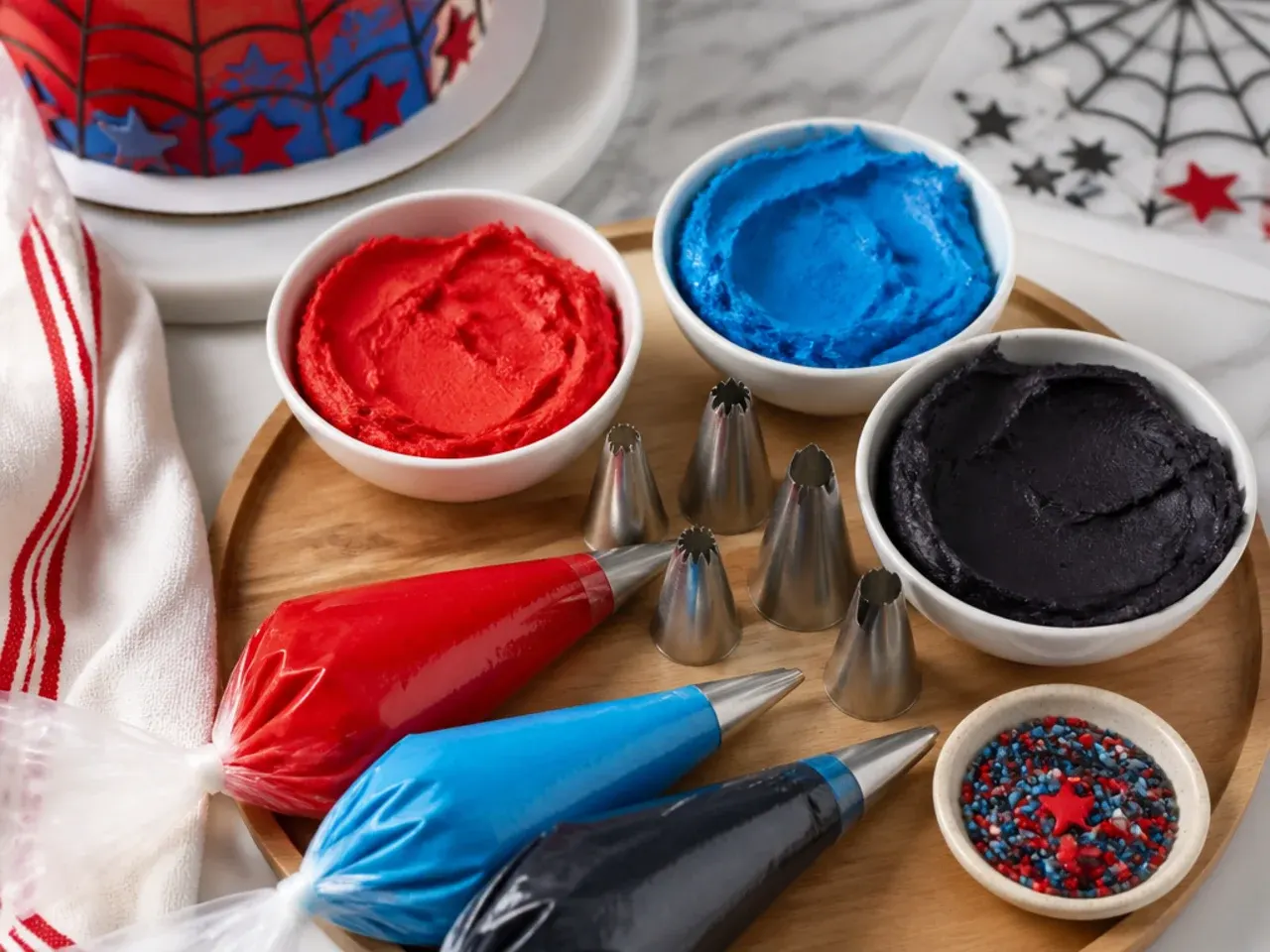 Decorating tools and coloured buttercream prepared for spiderman cake designs