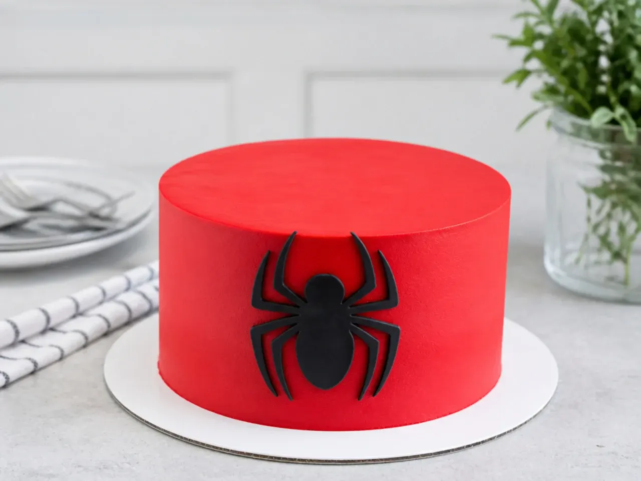 Minimal Spiderman cake for boys with a single black spider emblem on a smooth red surface