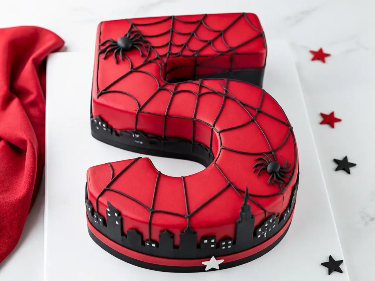 Playful number-shaped Spiderman cake for boys with a red and black web following the numeral