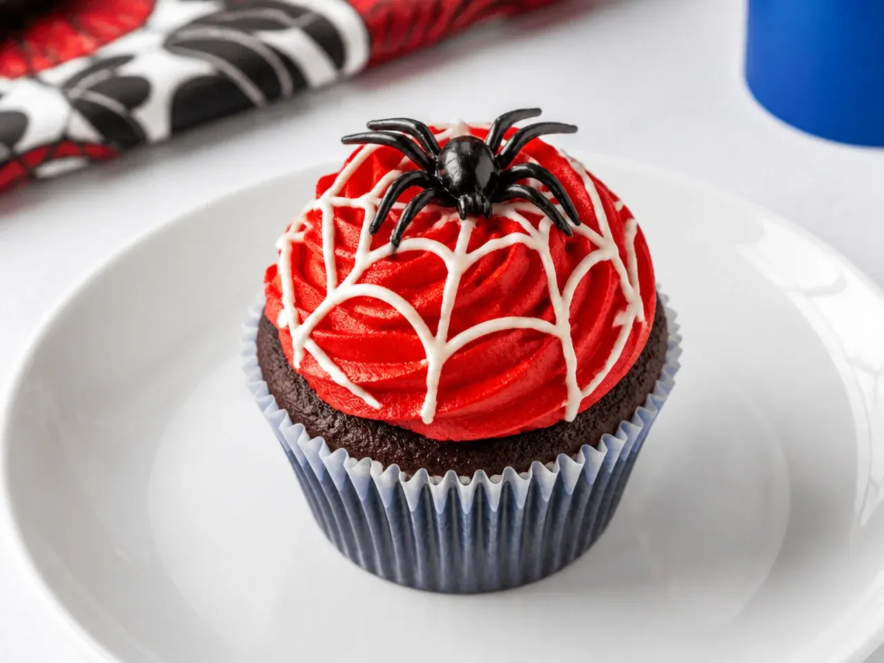 Playful Spiderman cupcakes topped with plastic spider rings and red frosting