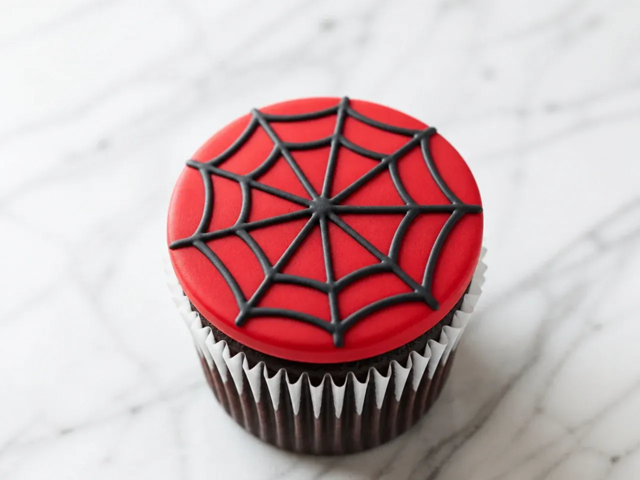 Modern Spiderman cupcake with a flat red fondant disc and geometric web