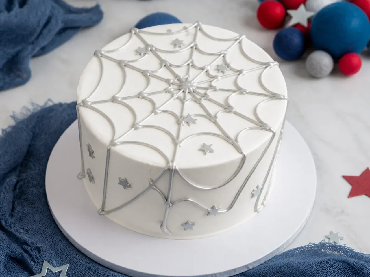 Elegant white smash cake with fine silver piped web, a subtle spiderman smash cake idea