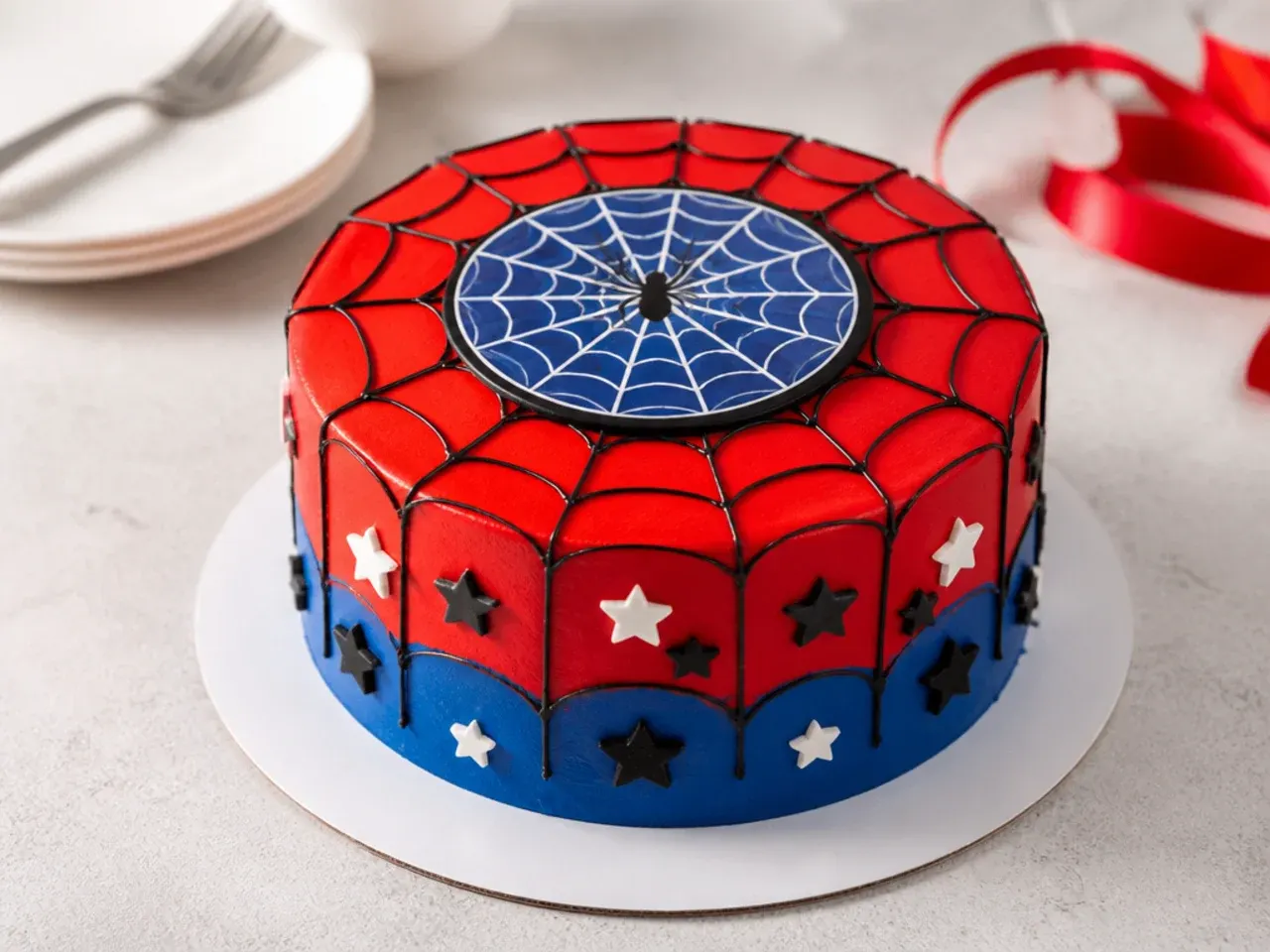 Store-bought Spiderman cake in red and blue with a printed web topper on a bakery board