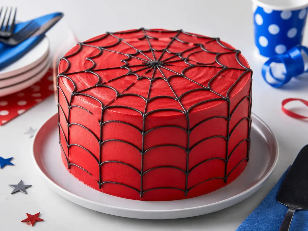 Homemade Spiderman-inspired cake with red buttercream and a hand-piped black web pattern