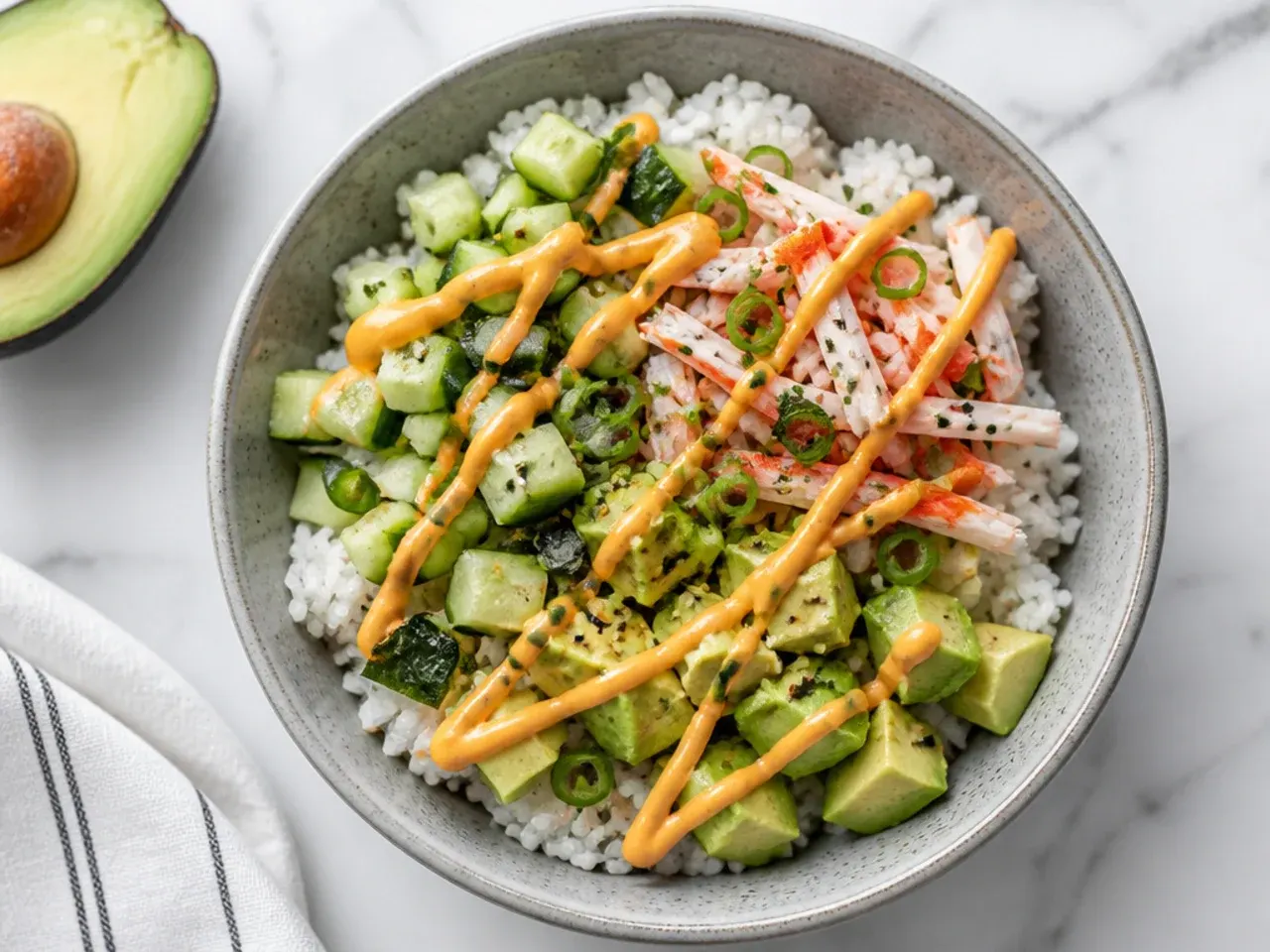 Overhead homemade sushi bowl with seasoned rice, crab, avocado, cucumber and spicy mayo zigzags showing how to make a sushi bowl at home